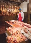 Butcher working in meat storage room at butchers shop — Stock Photo