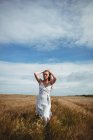 Жінка з руками в волоссі, що йде через пшеничне поле в сонячний день — стокове фото