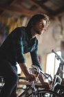 Meccanico cercando bicicletta in officina — Foto stock