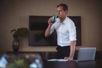 Концентрированный бизнесмен пьет воду во время работы в офисе — стоковое фото