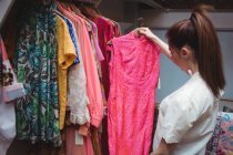 Жінка вибирає одяг на вішалці в магазині одягу — стокове фото