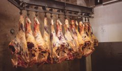 Peeled red meat hanging in the storage room at butchers shop — Stock Photo
