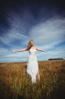 Жінка стоїть з простягнутими руками в пшеничному полі в сонячний день — стокове фото