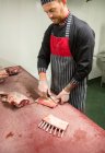 Мясник режет свиные ребрышки в мясной лавке — стоковое фото