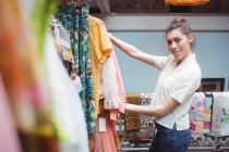 Портрет жінки, яка вибирає одяг на вішалці в магазині одягу — стокове фото