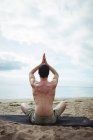 Вид ззаду людини, що виконує йогу на пляжі — стокове фото