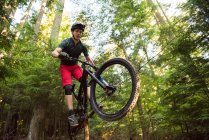 Cycliste masculin en forêt par une journée ensoleillée — Photo de stock