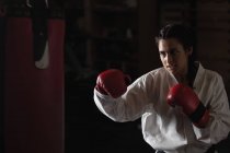 Ritratto di Donna che pratica karate con sacco da boxe in palestra — Foto stock