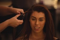 Женщина выпрямляет волосы в парикмахерской — стоковое фото