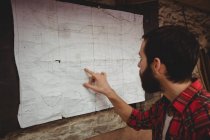 Man looking at blueprint on boatyard wall — Stock Photo