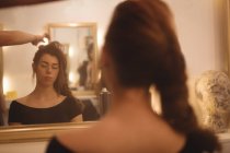 Reflexão de uma mulher bonita no espelho styling seu cabelo no salão — Fotografia de Stock