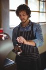 Офіціант за допомогою тампона, щоб пресувати мелену каву в портативний фільтр в кафе в майстерні — стокове фото