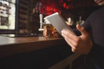 Средняя часть человека с помощью цифрового планшета в барной стойке в баре — стоковое фото