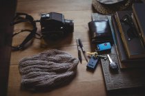 Chapeau de laine, appareil photo, clé, portefeuille, lunettes de soleil, journal intime et stylos sur la table — Photo de stock