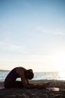 Вид збоку жінки заняттях йогою на пляжі сонячний день — стокове фото
