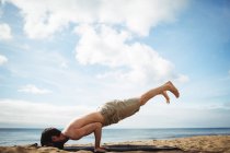 Homme effectuant du yoga sur la plage — Photo de stock