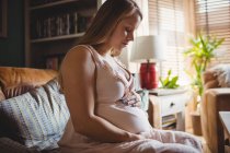 Seitenansicht einer schwangeren Frau, die es sich im heimischen Wohnzimmer gemütlich macht — Stockfoto