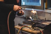 Cropped image of Glassblower giving final touch to piece of glass with glassblowing torch at glassblowing factory — Stock Photo