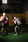 Vista lateral de dos boxeadores atléticos tailandeses practicando en el gimnasio - foto de stock