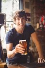 Ritratto di uomo che tiene un bicchiere di birra al bar — Foto stock