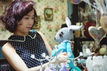 Stylish woman selecting a soft toy in antique shop — Stock Photo