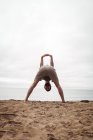 Man performing stretching exercise on beach — Stock Photo
