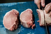Mano de carnicero rebanando carne en carnicería - foto de stock