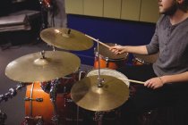 Studente maschio che suona il tamburo in uno studio — Foto stock