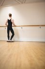 Vue arrière de Ballerino s'étirant sur la barre tout en pratiquant la danse de ballet en studio — Photo de stock