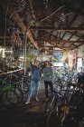 Mécanique examinant un vélo dans un atelier de vélo — Photo de stock