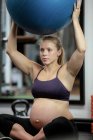 Schwangere trainiert mit Gymnastikball in Turnhalle — Stockfoto