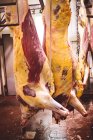 Carne vermelha descascada pendurada na arrecadação do talho — Fotografia de Stock