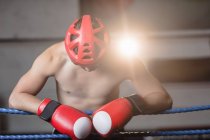 Сорочки боксера в захисних шоломи боксерські спираючись на тросах боксерський ринг в фітнес-студія — стокове фото