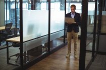 Бизнесмен, использующий ноутбук в офисном коридоре — стоковое фото
