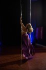 Vista trasera de la bailarina polaca practicando pole dance en estudio - foto de stock