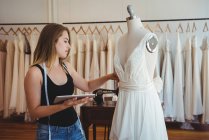 Жіночий дизайнер моди, що налаштовує сукню на манекен в студії — стокове фото