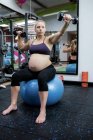 Mulher grávida levantando halteres no ginásio — Fotografia de Stock