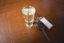 Glass of tequila shot with car key in bar counter at bar — Stock Photo