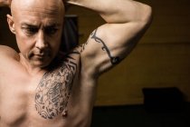 Close up of tattooed shirtless thai boxer posing in gym — Stock Photo