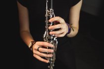 Mi-section de la femme jouant une clarinette à l'école de musique — Photo de stock