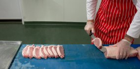 Section médiane du boucher tranchant la viande à la boucherie — Photo de stock