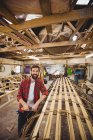 Portrait of man standing near a wooden boat frame at boatyard — Stock Photo