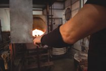 Cropped image of Glassblower heating glass in furnace at glassblowing factory — Stock Photo
