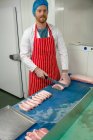 Portrait of butcher slicing meat at butchers shop — Stock Photo