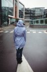 Visão traseira da mulher de pé na rua durante a chuva — Fotografia de Stock