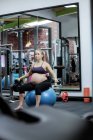 Femme enceinte soulevant haltères à la salle de gym — Photo de stock