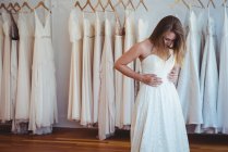 Mulher bonita tentando em vestido de noiva em uma loja em estúdio — Fotografia de Stock