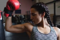Female boxer in boxing gloves showing muscle in fitness studio — Stock Photo