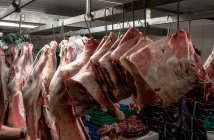 Carne roja pelada colgada en el almacén de la carnicería - foto de stock