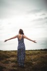 Жінка позаду, що стоїть з простягнутими руками на скелі біля моря — стокове фото